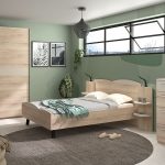 Photo d'ambiance d'une chambre avec un cadre de lit, une tête de lit avec étagère et lisseuse, une chiffonnier et une armoire. Le tout avec une finition en bois chêne Tronçais. La collection s'inspire des vagues avec une teinte blanc crème.