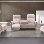 Photo d'ambiance d'un salon présentant un ensemble de canapés composé d'un canapés 2 places relax électrique, un canapé 3 places avec 2 relax électrique et un fauteuil relax électrique. Le revêtement en tissu est dans des tons rose et mauve.